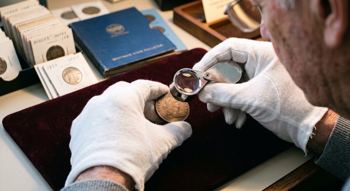 Professional numismatist examining an early 1800s U.S. Large Cent coin with a magnifying loupe